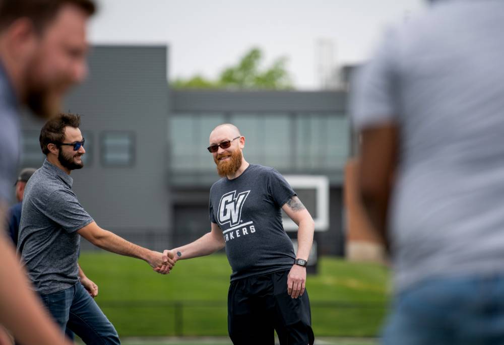 Two opponents shaking hands at the end of a cornhole match